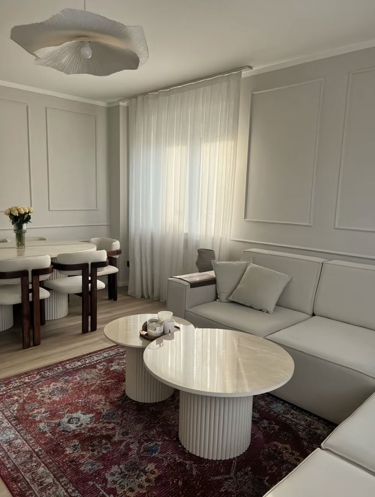 Light living and dining room with wall moulding, a modular sofa and deep red vintage rug